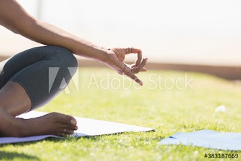 Close up woman meditating with hand in gyan mudra on sunny lawn