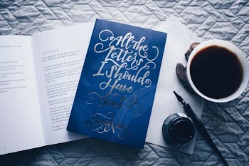 closed All the Letters I Should Have Sent novel book beside filled white cup