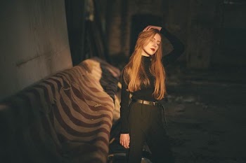closed eye woman standing near wall in dimmed room