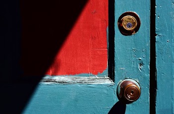 closed teal wooden door with brass-colored door knob