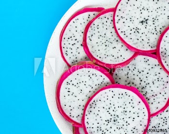 Closeup of a plate of dragon fruit slices on blue background