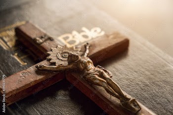 Closeup of wooden Christian cross on Bible, vintage tone. Symbol of God and goodness.