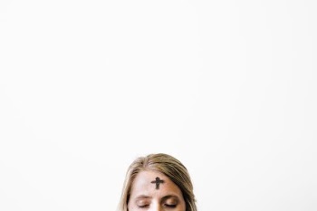 closeup photo of cross print on woman's forehead