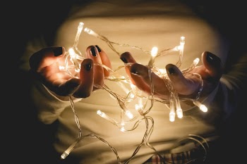 Closeup Photo of Person Wearing White Long-sleeved Shirt Holding Turned on String Lights