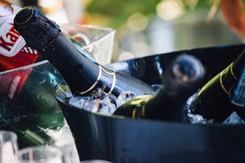closeup photo of three wine bottles on bucket with ice
