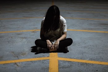 closeup photo of woman sitting on concrete pavement