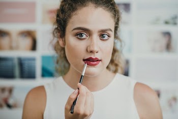 closeup photo of woman using lipstick