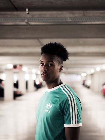 closeup photography of man in teal and white adidas crew-neck t-shirt