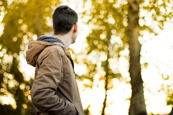 Closeup Photography of Man Wearing Blue Jacket Under Brown Leaf Trees