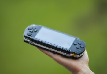 Closeup Photography of Person Holding Black Sony Psp Handheld Console