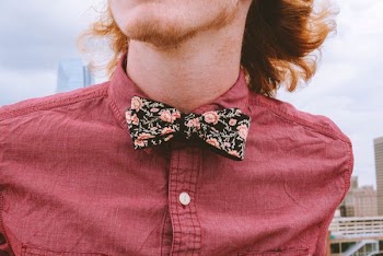 closeup photography of person wearing floral bowtie and red dress shirt