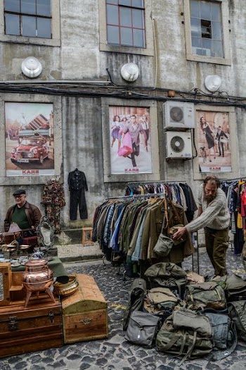clothes and bags displayed on road near building during daytime