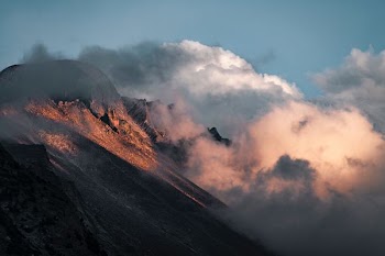 clouds enveloping brown rockhill during daytime