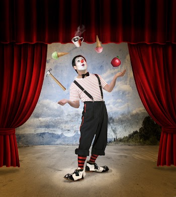 Clown performing on stage with red curtains