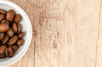 Coffee Beans on White Ceramic Bowl on Top of Brown Wooden Surface
