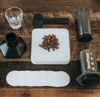 coffee beans on white plastic and black Aero Press set