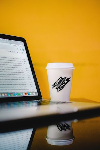 coffee & john-printed cup with lid beside MacBook