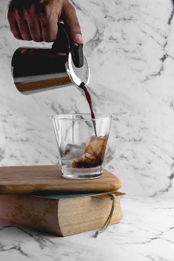 Cold brew coffee! 
I believe we've got something really interesting to beat the heat!  This is for all of you who really need their caffeine fix but the heat just makes a hot brew unappealing. After a couple of experiments with easily available coffee and brewing method, I and my friend arrived at something we like. 
Shot this with two LED bulbs in an octabox on camera right. It had to be a pouring shot to capture the mood of anticipation before we get to the brew and have it. I can just imagine the smells wafting around and the sound of coffee being poured onto clinking ice!