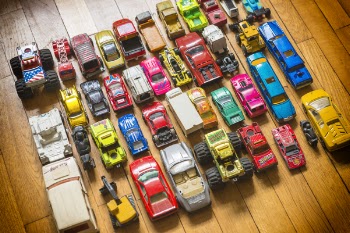 Collection of different types of used toy cars on wooden background.