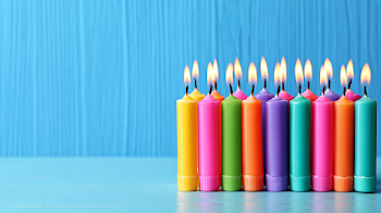 Colorful Lit Birthday Candles on Blue Tabletop