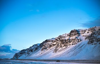 Compact Car Drives Past Iceland Hill