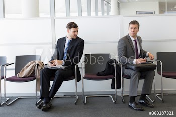 Competing businessmen waiting for job interview in office lobby