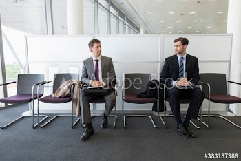 Competing businessmen waiting for job interview in office lobby