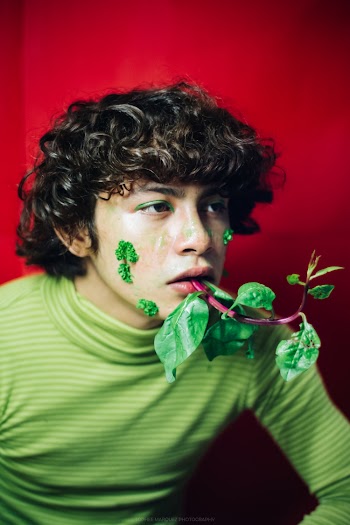 Concept Photography Of A Young Man In Green Turtle Neck Shirt With Green Leafy Vegetable On His Mouth And Face
