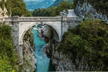 Concrete Bridge over Clear Blue River Beside Mountain