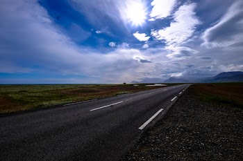 Concrete Road Between Grass Fields