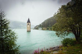 concrete tower surrounded by water near land with trees