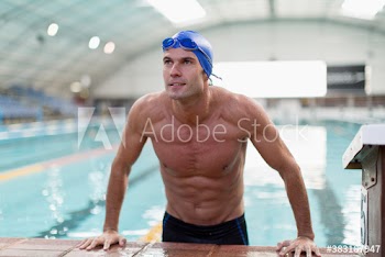 Confident athletic male swimmer at edge of swimming pool