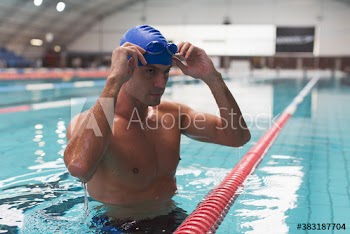 Confident athletic male swimmer preparing in swimming pool