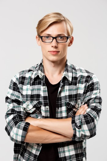 Confident blond handsome young man in glasses wearing casual plaid shirt with hands crossed on chest on grey wall Free Photo