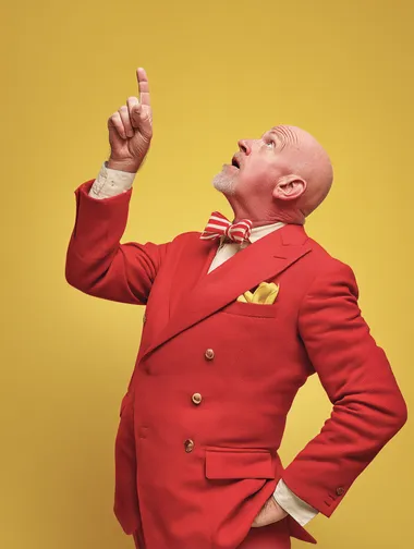 Confident Middle-Aged Man in Red Suit Pointing Upward Confident Middle-Aged Man in Red Suit Pointing Upward