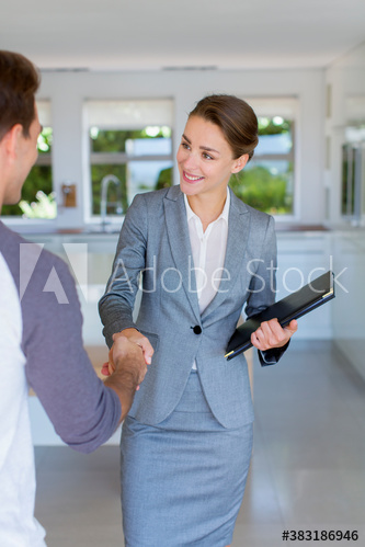 Confident realtor shaking hands with man in house