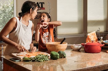 Cooking with Mom and daughter while laughing together in the kitchen 