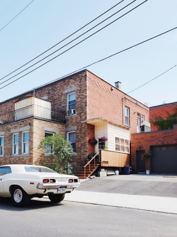 Cool, retro white car beside a sunny and bright house under a light blue sky. 