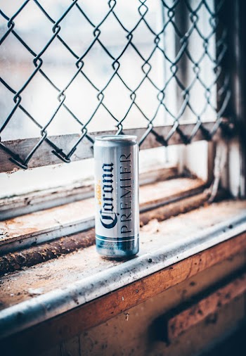 Corona Premier Can Beside Chain Link Gate