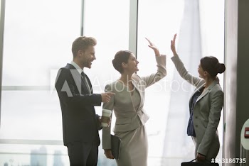 Corporate business people high-fiving in office window
