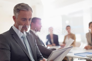 Corporate businessman reading paperwork in conference room meeting