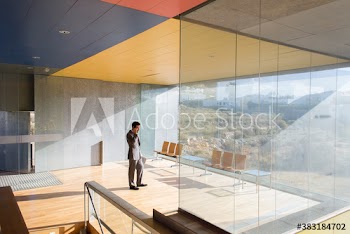 Corporate businessman talking on smart phone in sunny modern office