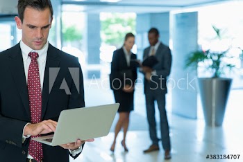 Corporate businessman using laptop in office lobby