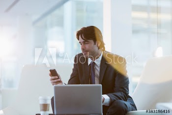 Corporate businessman using smart phone at laptop