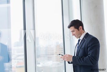 Corporate businessman using smart phone in highrise window