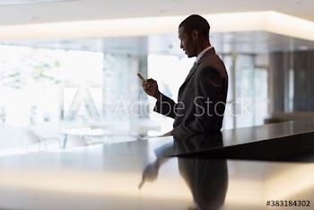 Corporate businessman using smart phone in modern office