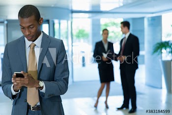 Corporate businessman using smart phone in office lobby