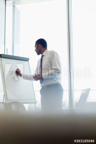 Corporate businessman writing on flipchart in conference room