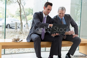 Corporate businessmen using laptop in lobby