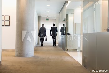 Corporate businessmen walking in modern corridor